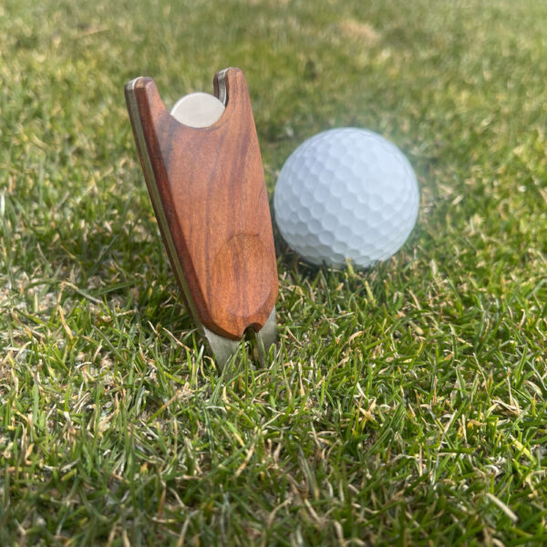 wood handle divot repair tool in grass with golf ball